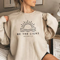 Women's crew neck sweatshirt with sun and wave graphic and Be the Light text