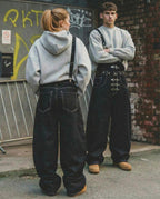 Black denim bib jeans with asymmetric shoulder strap, buckle details and wide legs