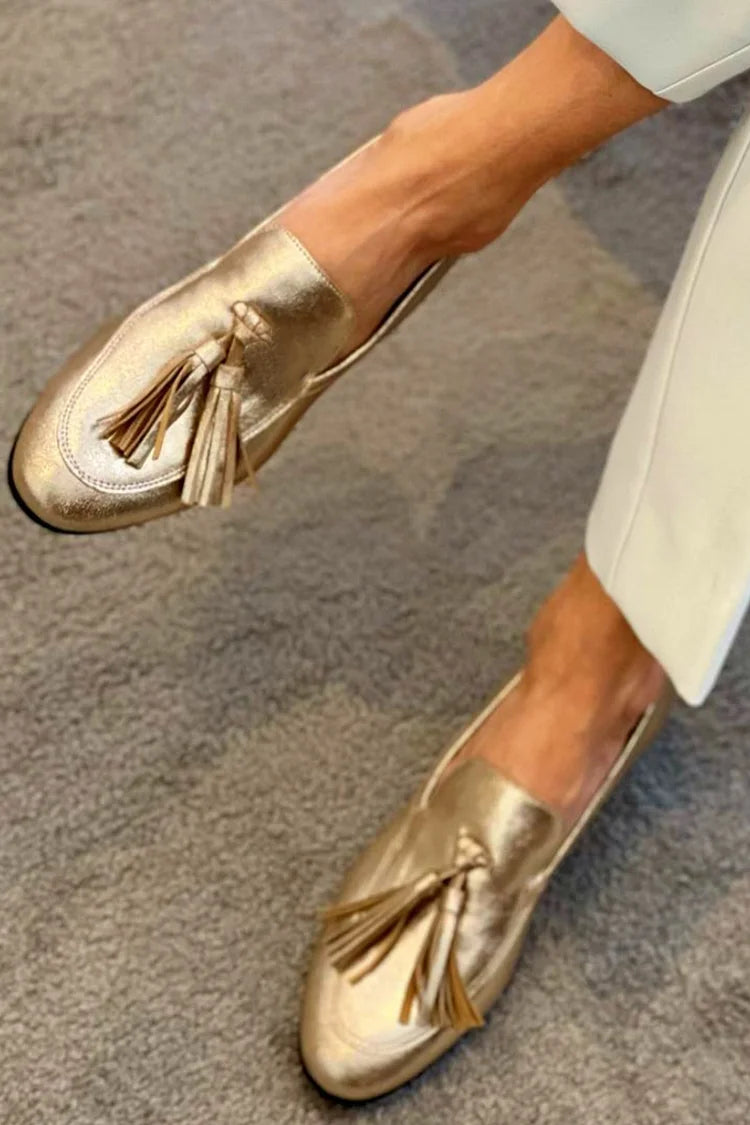 Women's gold metallic loafers with tassel details and flat soles