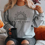 Women's crew neck sweatshirt with sun and wave graphic and Be the Light text