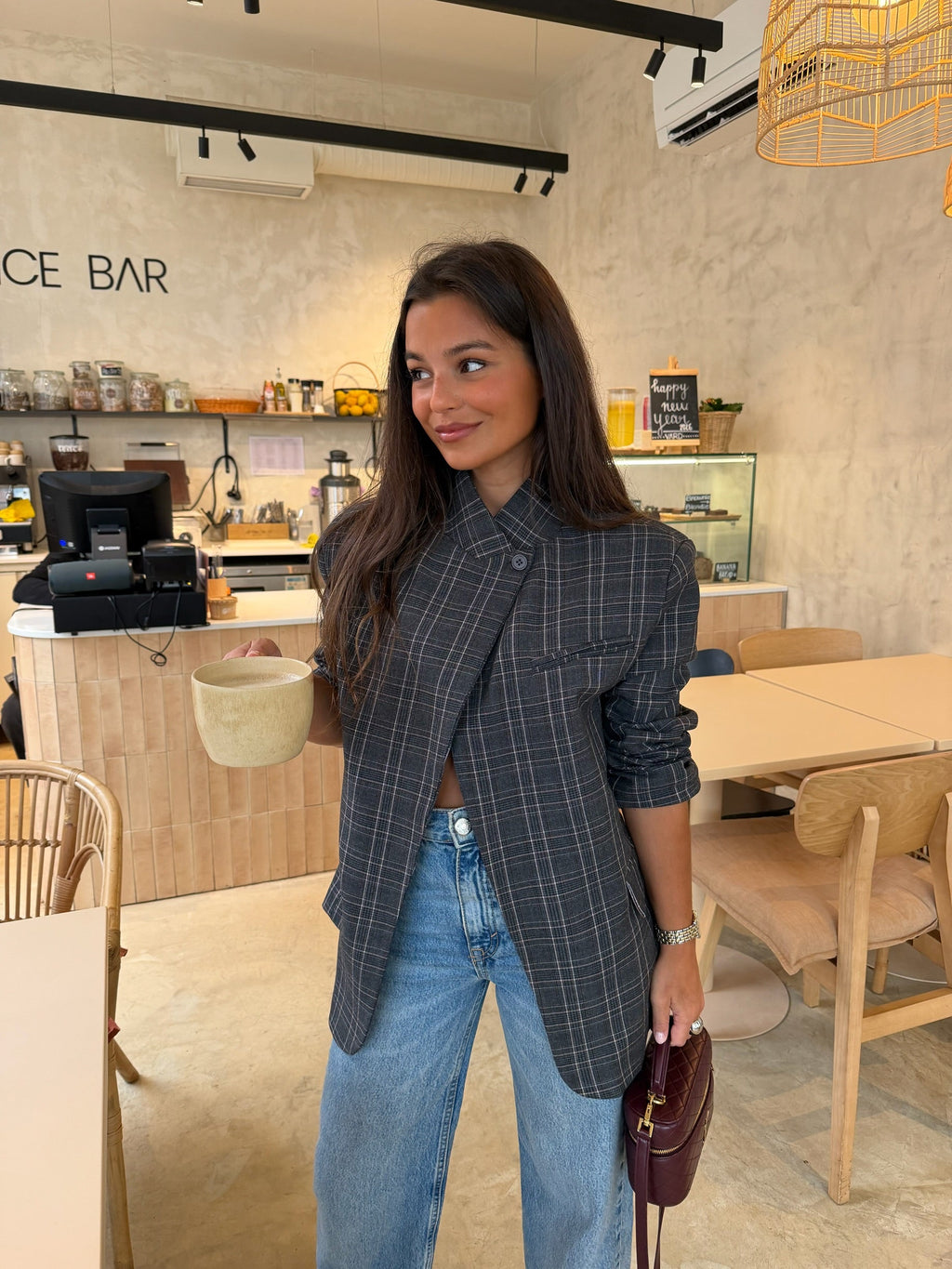 Woman wearing a grey checked plaid asymmetric blazer with long sleeves