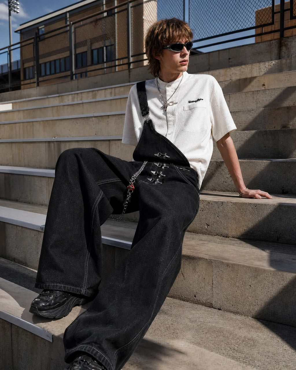 Black denim bib jeans with asymmetric shoulder strap, buckle details and wide legs