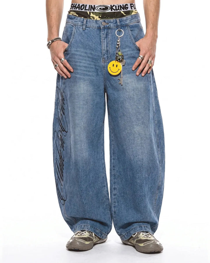 Light blue barrel jeans with script graphic on the left leg