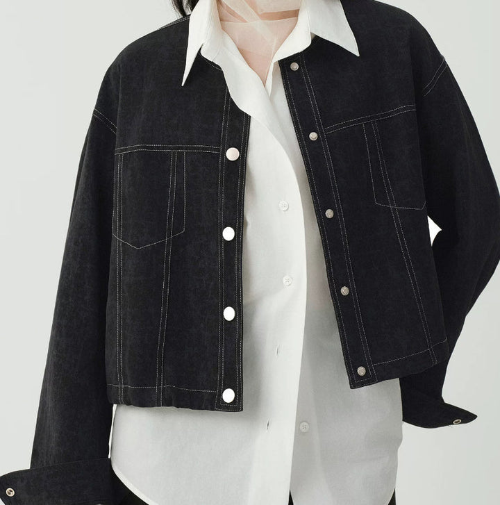 Women's cropped dark denim jacket with long sleeves and front pockets