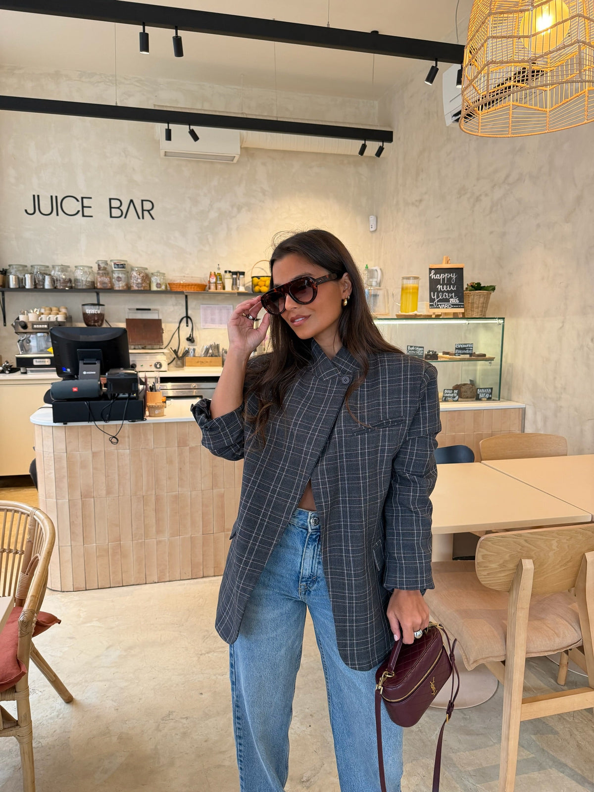 Woman wearing a grey checked plaid asymmetric blazer with long sleeves