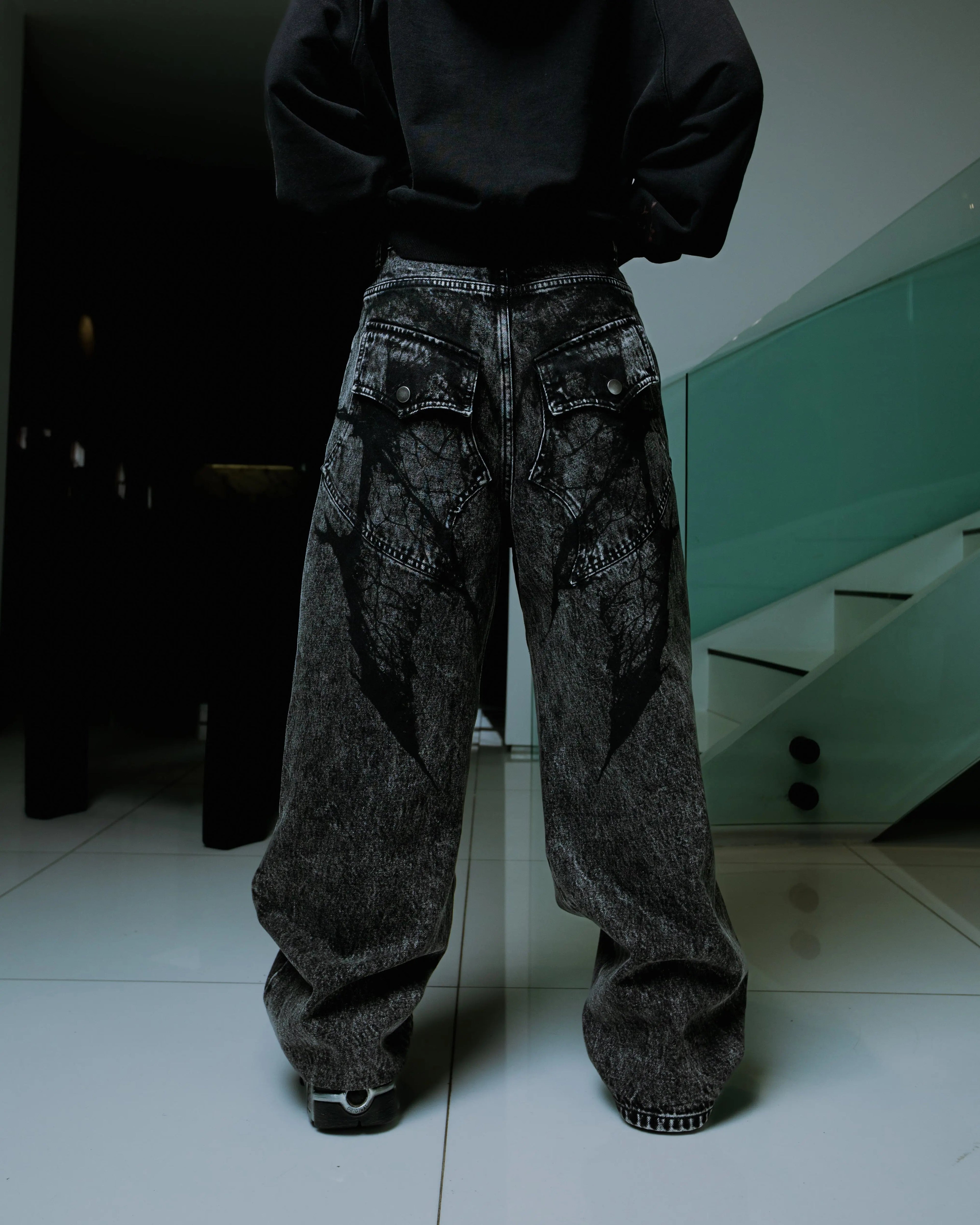 Women's black wide-leg jeans with graphic printed panels and flap pockets