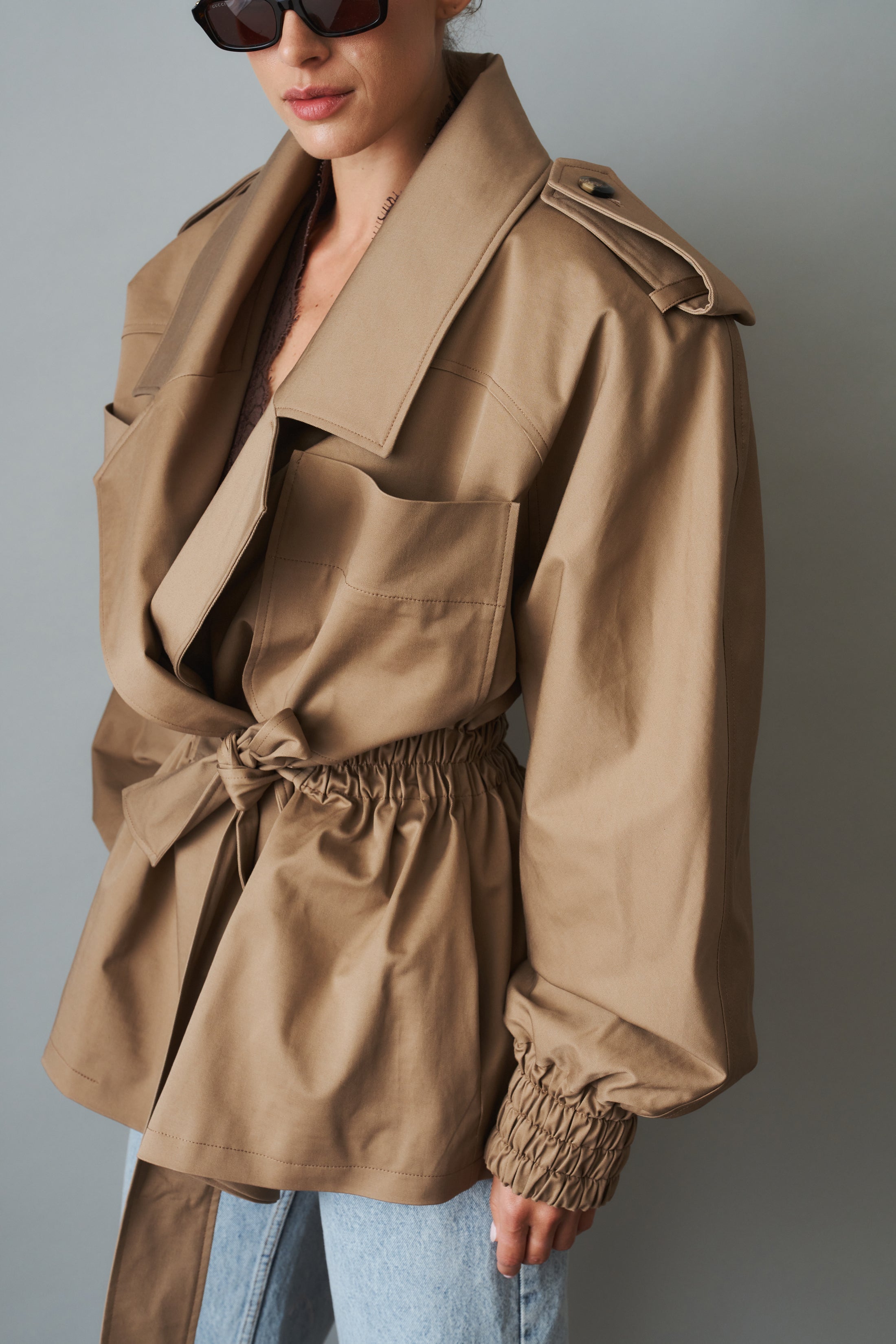 Women's khaki belted trench jacket with wide lapels and flap pockets