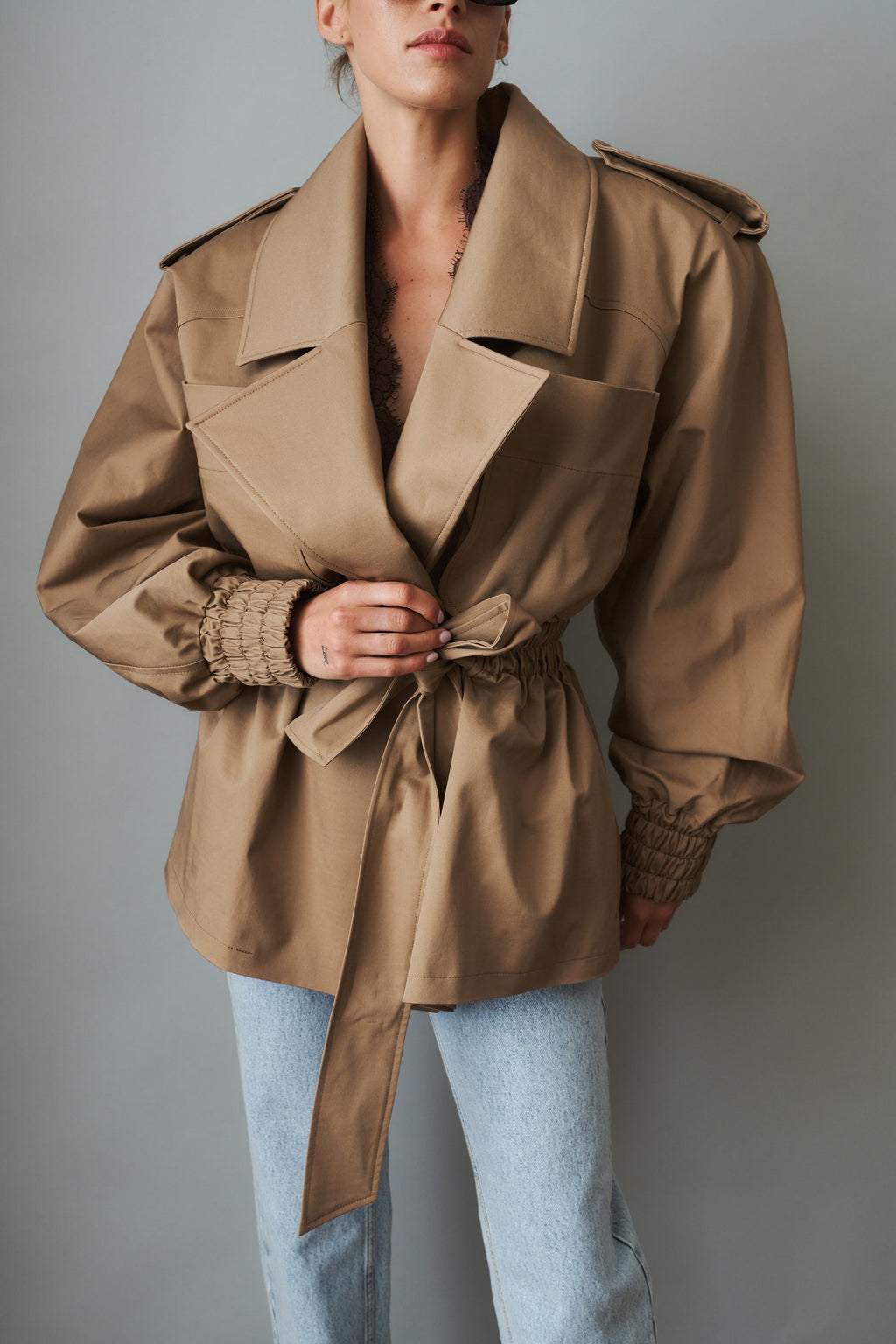 Women's khaki belted trench jacket with wide lapels and flap pockets