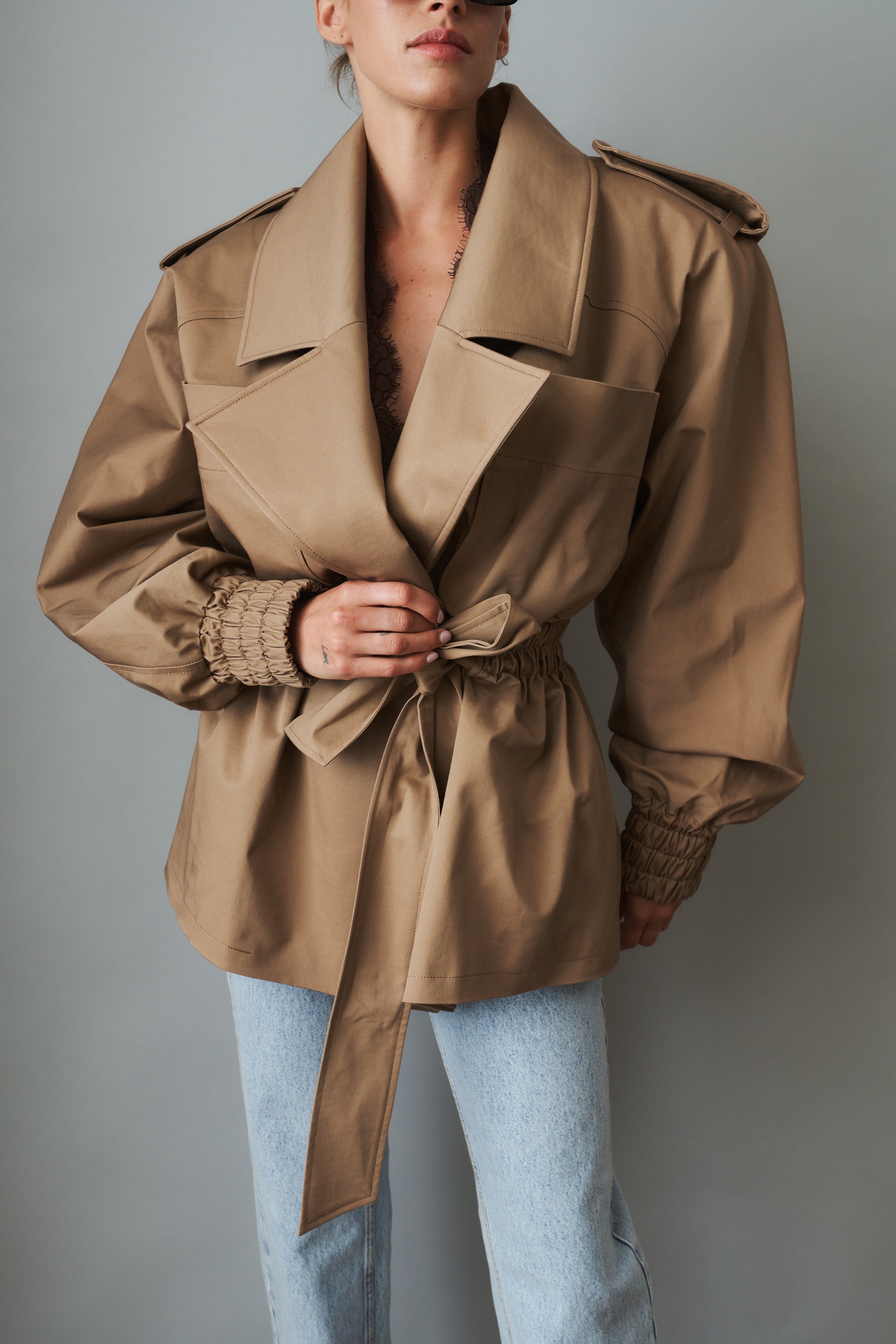 Women's khaki belted trench jacket with wide lapels and flap pockets