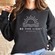 Women's crew neck sweatshirt with sun and wave graphic and Be the Light text
