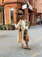 Woman wearing a long beige trench coat with lapels and a button front