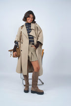 Woman wearing a long beige trench coat with lapels and a button front