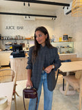 Woman wearing a grey checked plaid asymmetric blazer with long sleeves