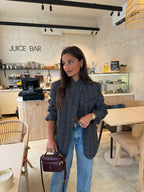 Woman wearing a grey checked plaid asymmetric blazer with long sleeves