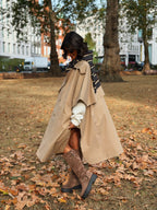 Woman wearing a long beige trench coat with lapels and a button front