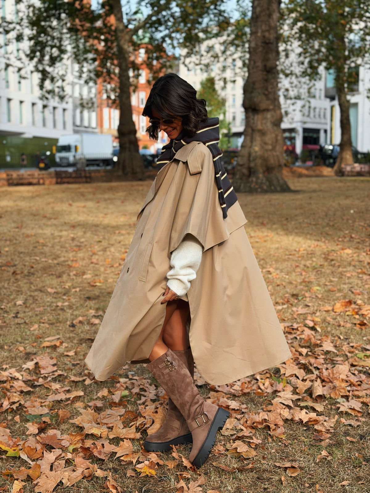 Woman wearing a long beige trench coat with lapels and a button front