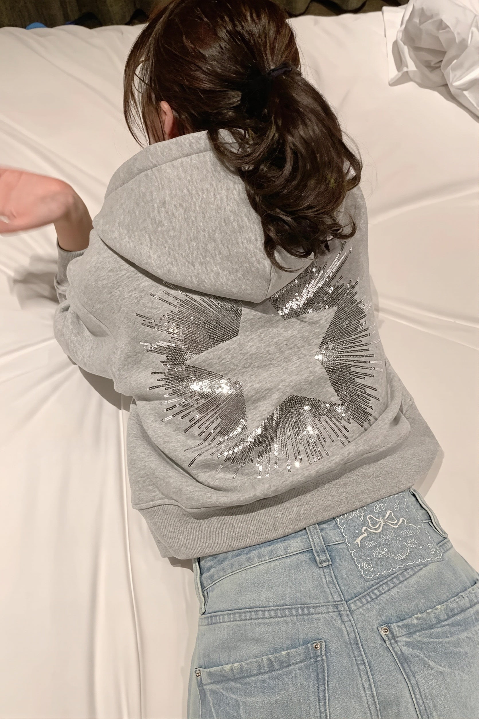 Cropped hooded pullover with long sleeves and a large sequin star design on the back