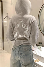 Cropped hooded pullover with long sleeves and a large sequin star design on the back