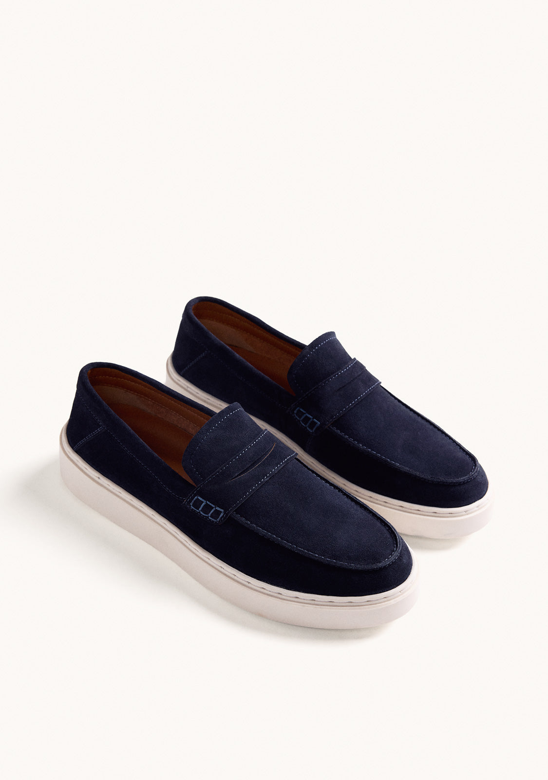 Navy slip-on penny loafers with decorative strap detail and contrasting flat soles