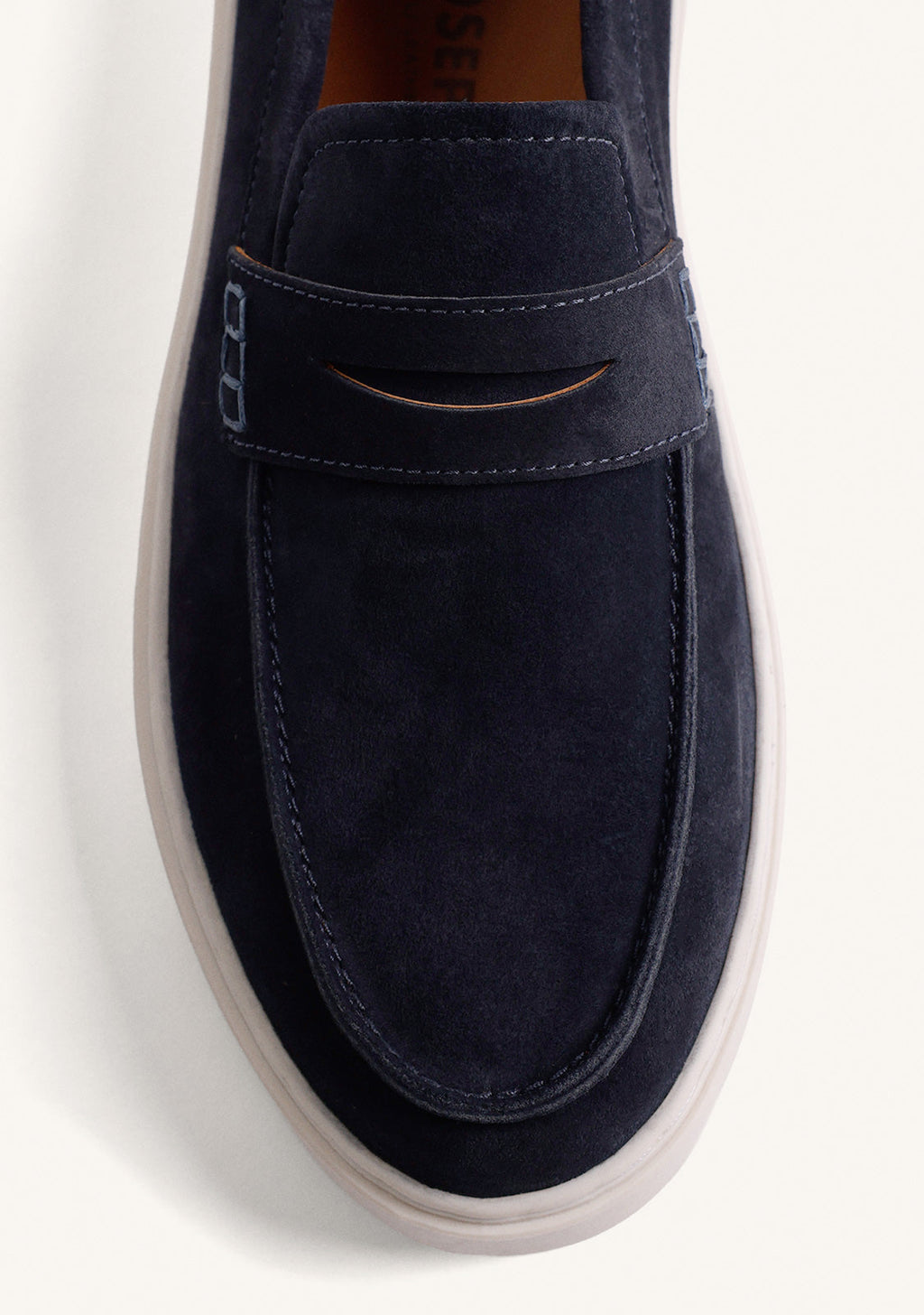 Navy slip-on penny loafers with decorative strap detail and contrasting flat soles