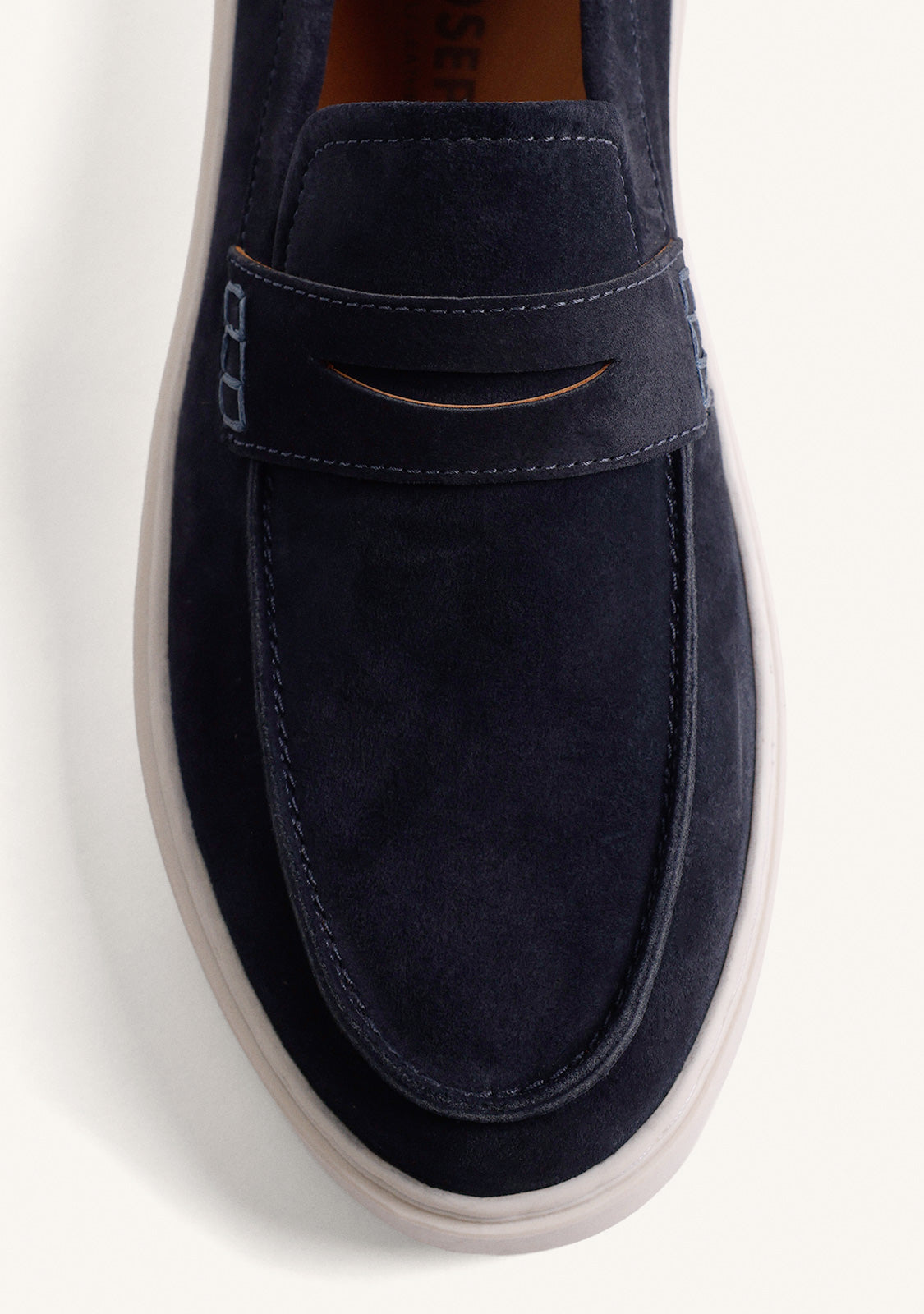 Navy slip-on penny loafers with decorative strap detail and contrasting flat soles