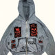 Men's grey zip-up hoodie with hood, graphic patches and front pockets