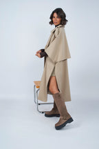 Woman wearing a long beige trench coat with lapels and a button front