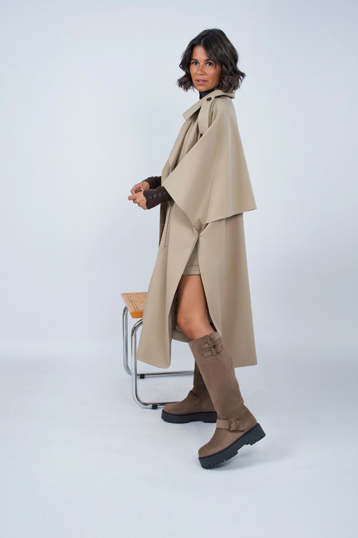 Woman wearing a long beige trench coat with lapels and a button front