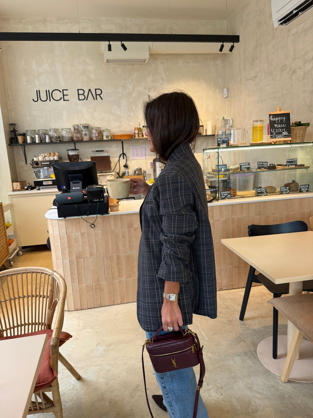 Woman wearing a grey checked plaid asymmetric blazer with long sleeves