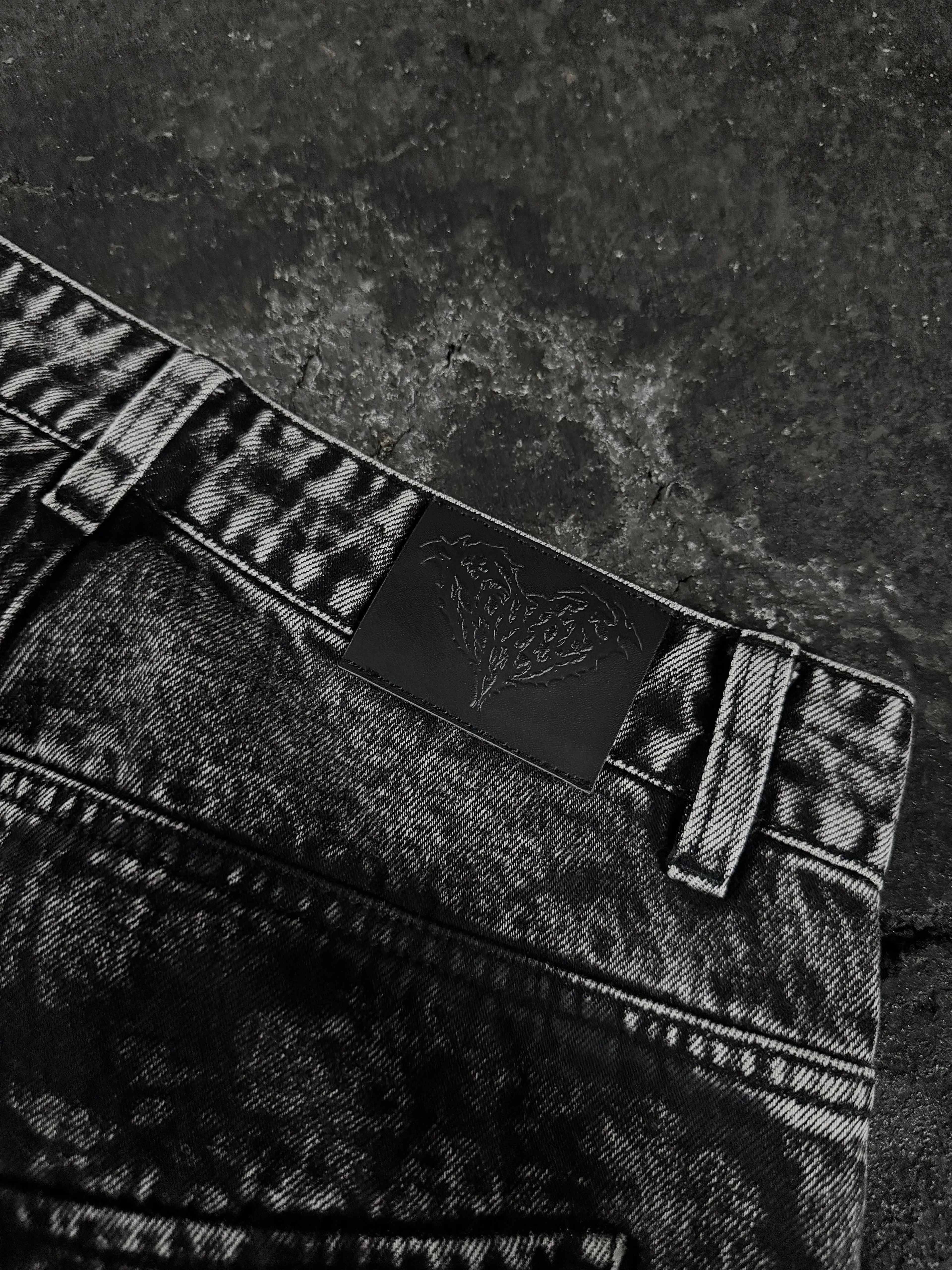 Women's black wide-leg jeans with graphic printed panels and flap pockets