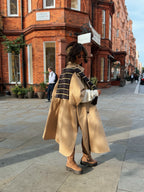 Woman wearing a long beige trench coat with lapels and a button front