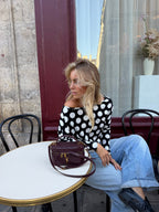 Women's black and white polka dot top with boat neckline and long sleeves