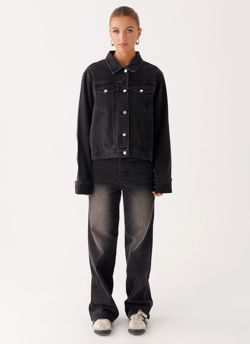 Woman wearing a charcoal oversized denim jacket with long sleeves and chest pockets