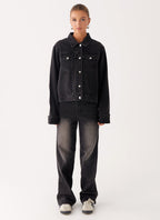 Woman wearing a charcoal oversized denim jacket with long sleeves and chest pockets