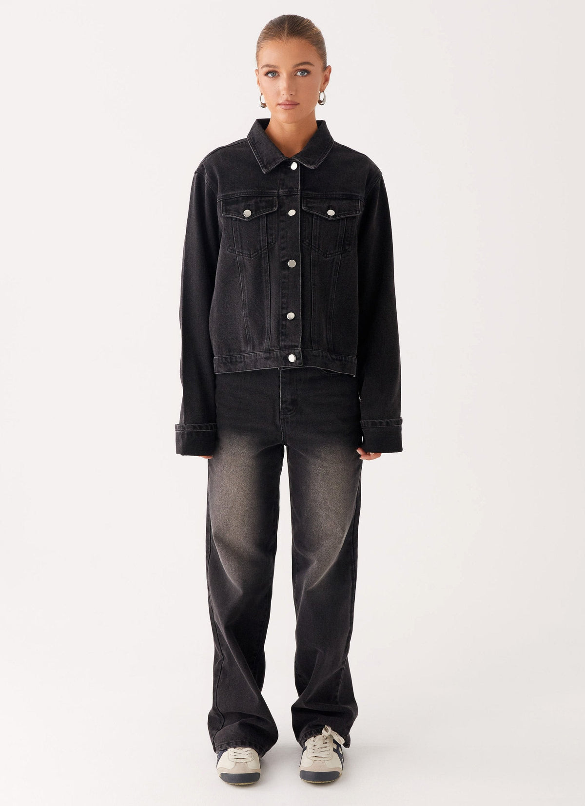 Woman wearing a charcoal oversized denim jacket with long sleeves and chest pockets