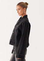 Woman wearing a charcoal oversized denim jacket with long sleeves and chest pockets