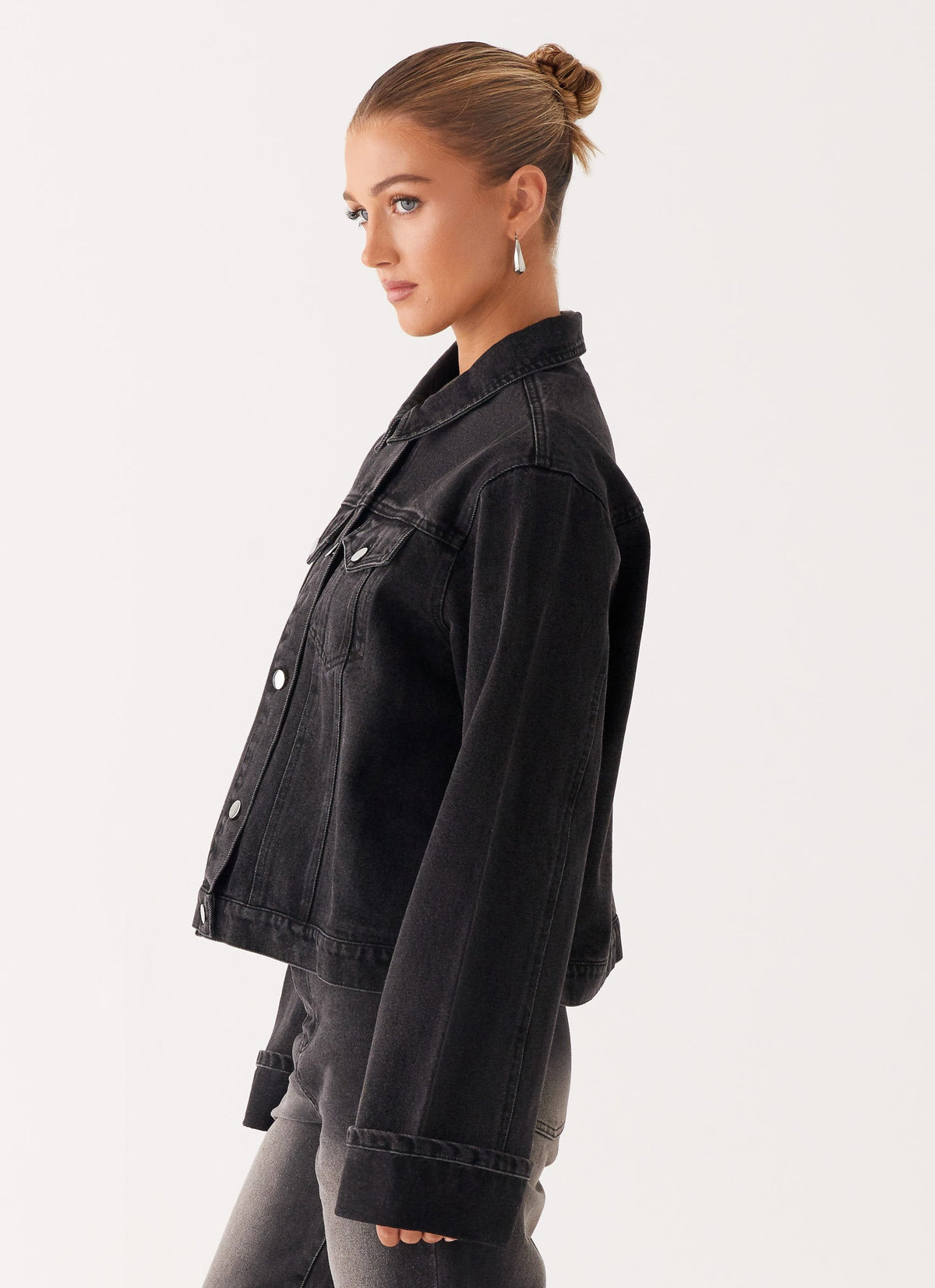 Woman wearing a charcoal oversized denim jacket with long sleeves and chest pockets