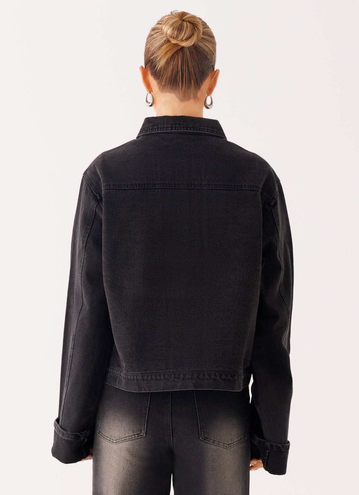 Woman wearing a charcoal oversized denim jacket with long sleeves and chest pockets