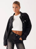 Woman wearing a charcoal oversized denim jacket with long sleeves and chest pockets
