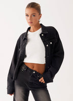 Woman wearing a charcoal oversized denim jacket with long sleeves and chest pockets