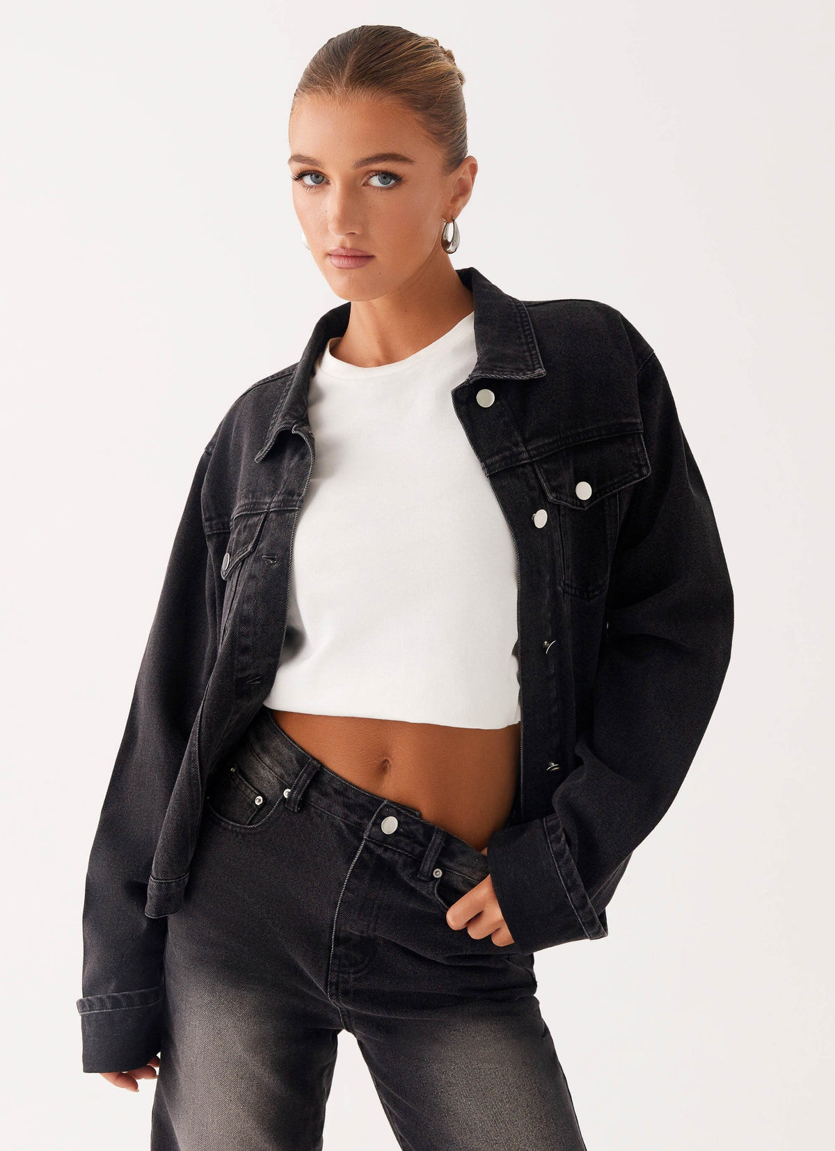 Woman wearing a charcoal oversized denim jacket with long sleeves and chest pockets