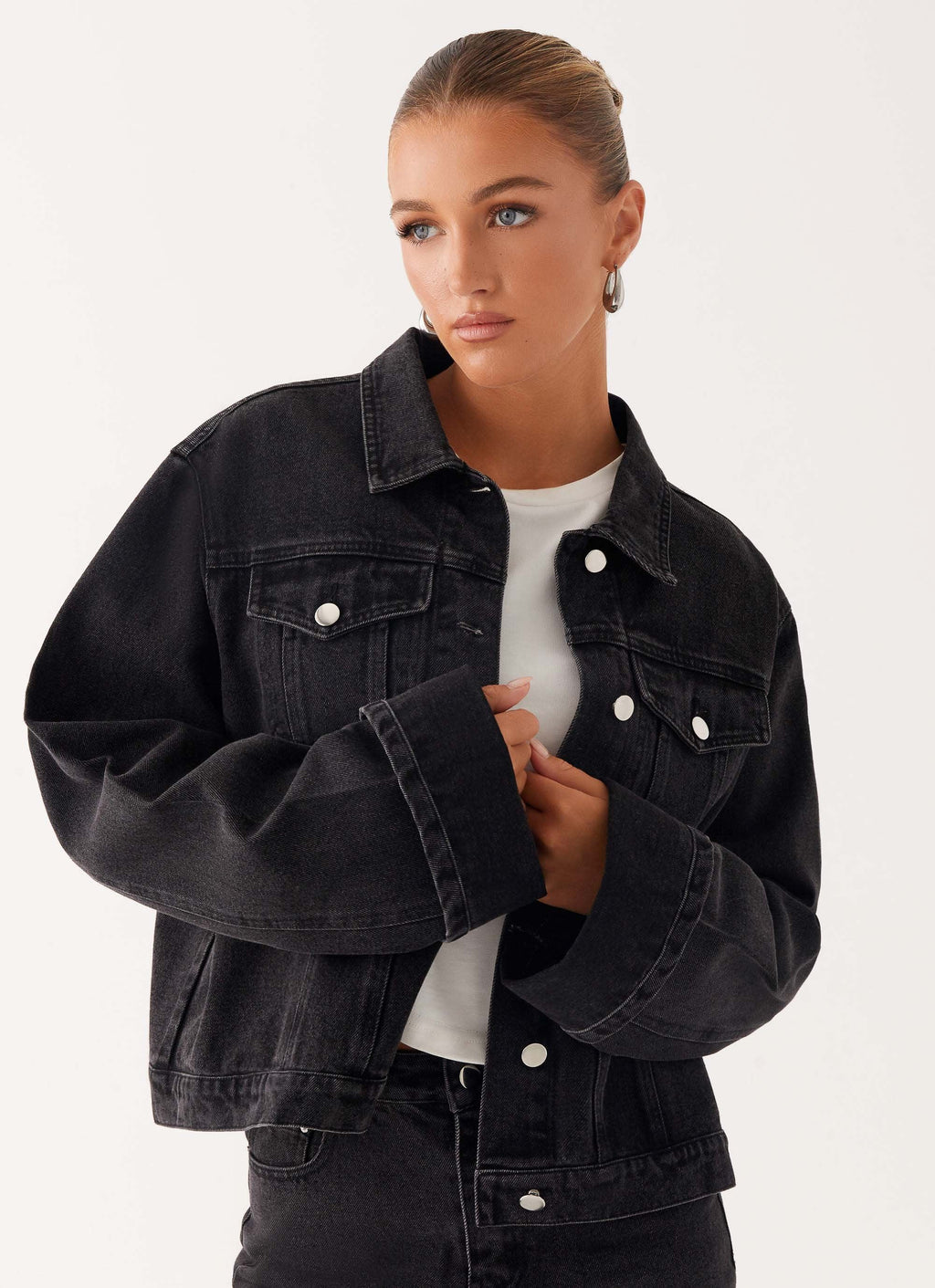 Woman wearing a charcoal oversized denim jacket with long sleeves and chest pockets