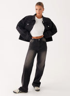 Woman wearing a charcoal oversized denim jacket with long sleeves and chest pockets
