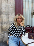 Women's black and white polka dot top with boat neckline and long sleeves