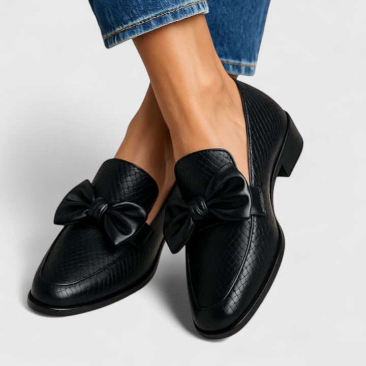 Black loafers with large bow details and textured uppers