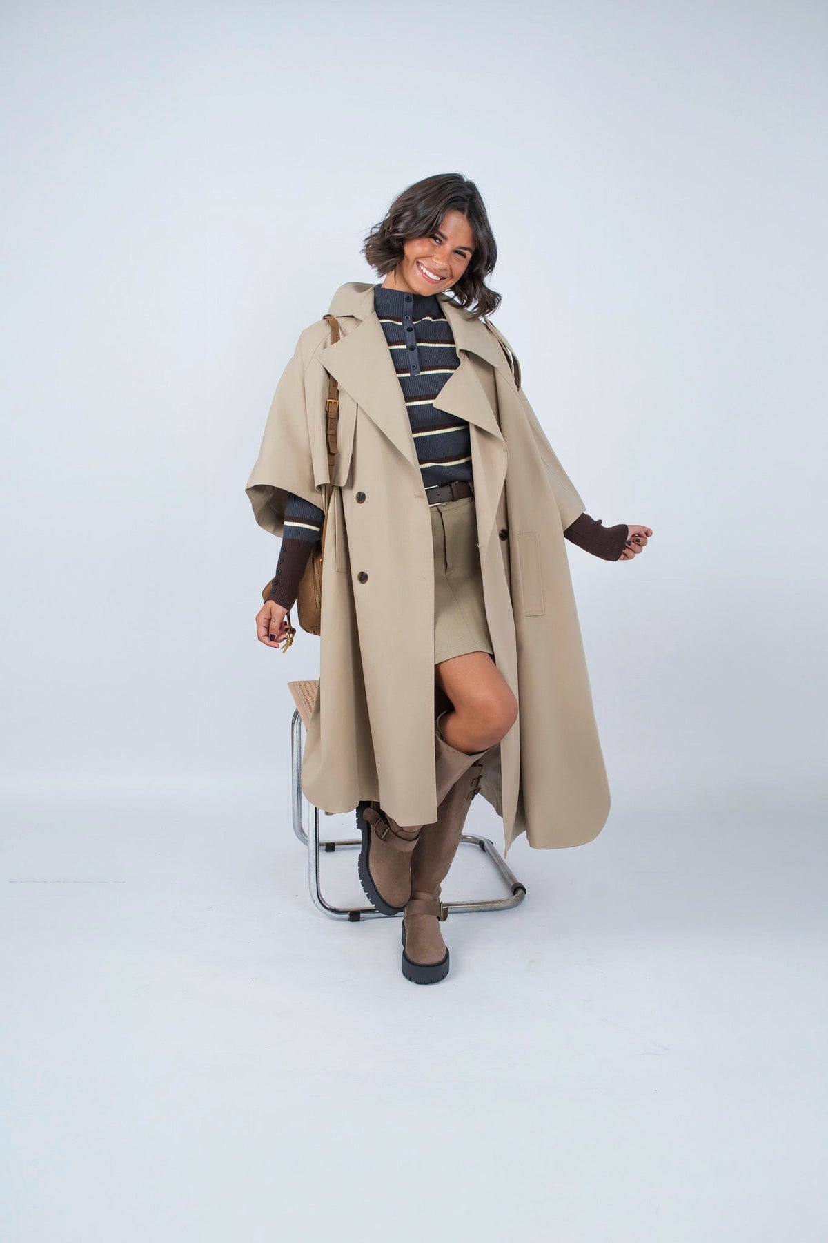 Woman wearing a long beige trench coat with lapels and a button front