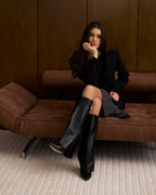 Women's black knee-high boots with pointed toes and buckle strap