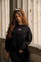 Women's black crewneck sweatshirt with pink chest logo