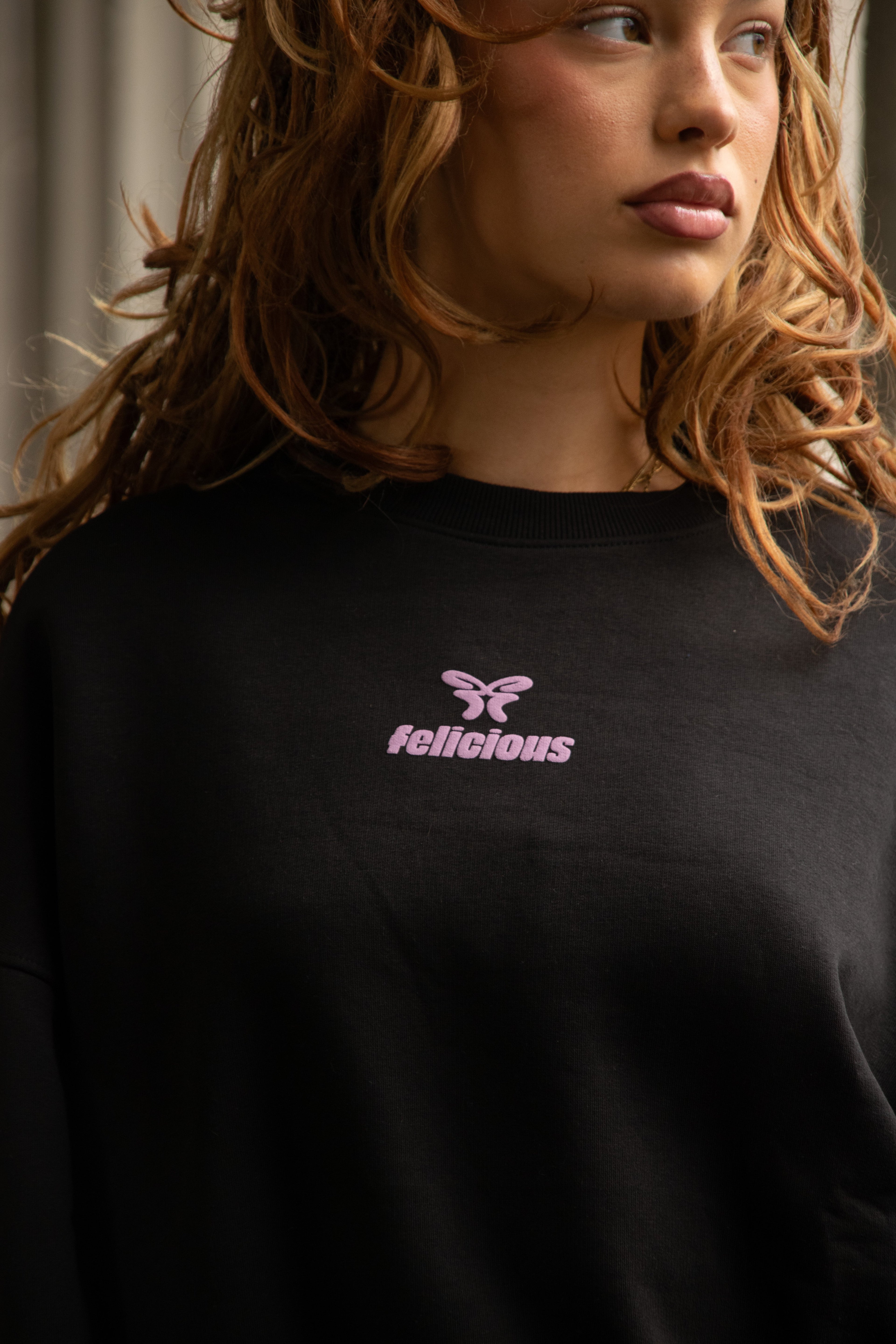 Women's black crewneck sweatshirt with pink chest logo