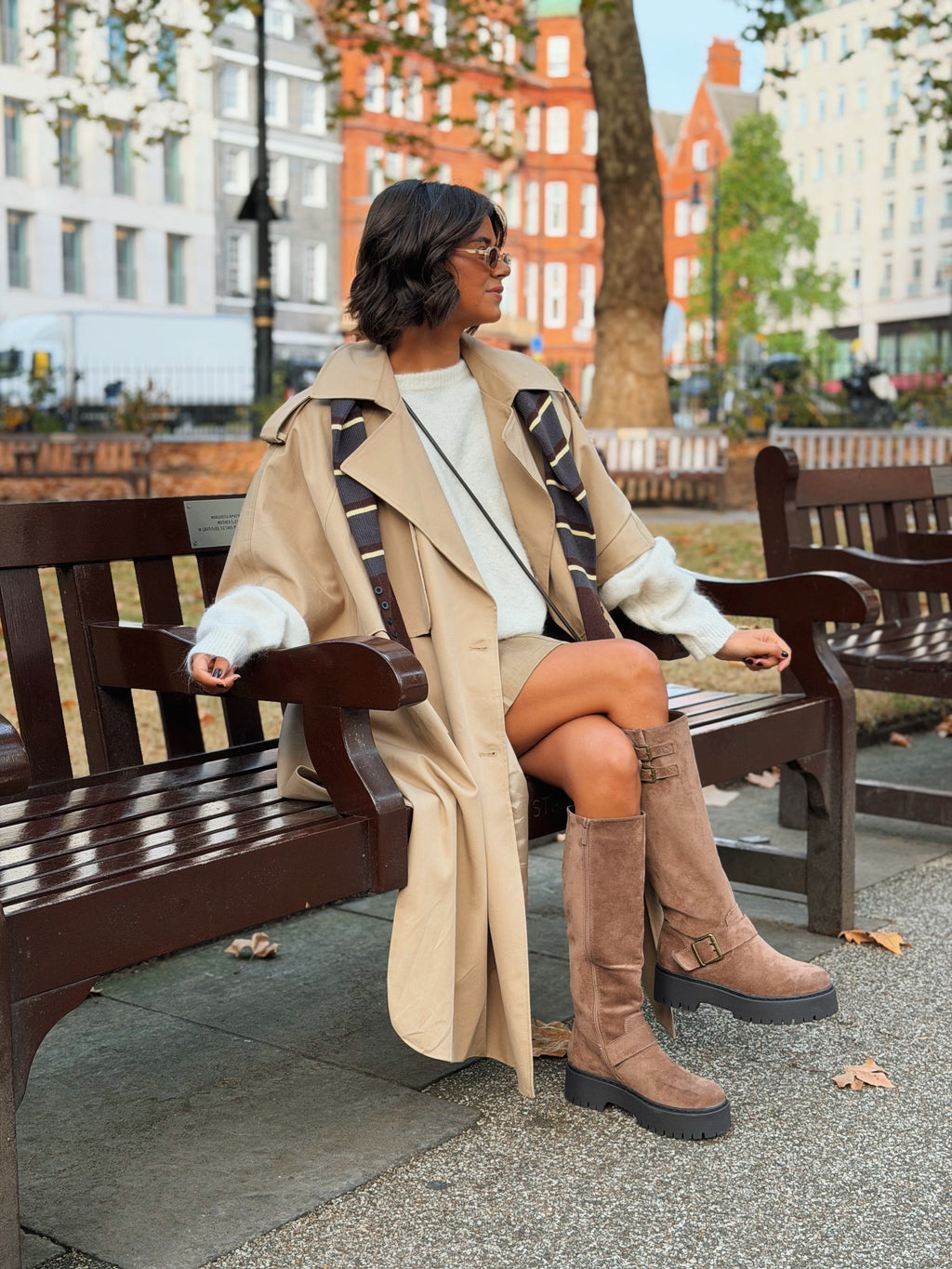 Woman wearing a long beige trench coat with lapels and a button front